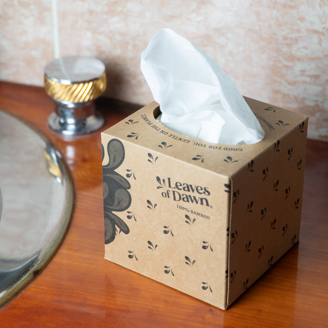 Leaves of Dawn bamboo tissue papers open box, on a wooden sink surface.